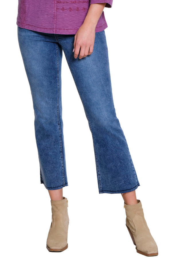 Person wearing blue jeans and beige boots on a white background