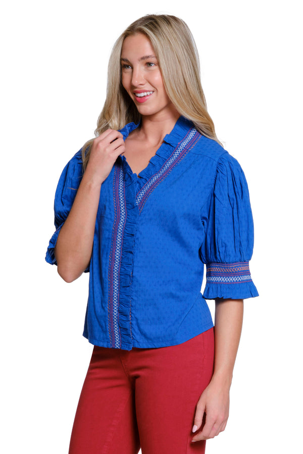 Woman wearing a blue blouse with ruffled sleeves on a white background