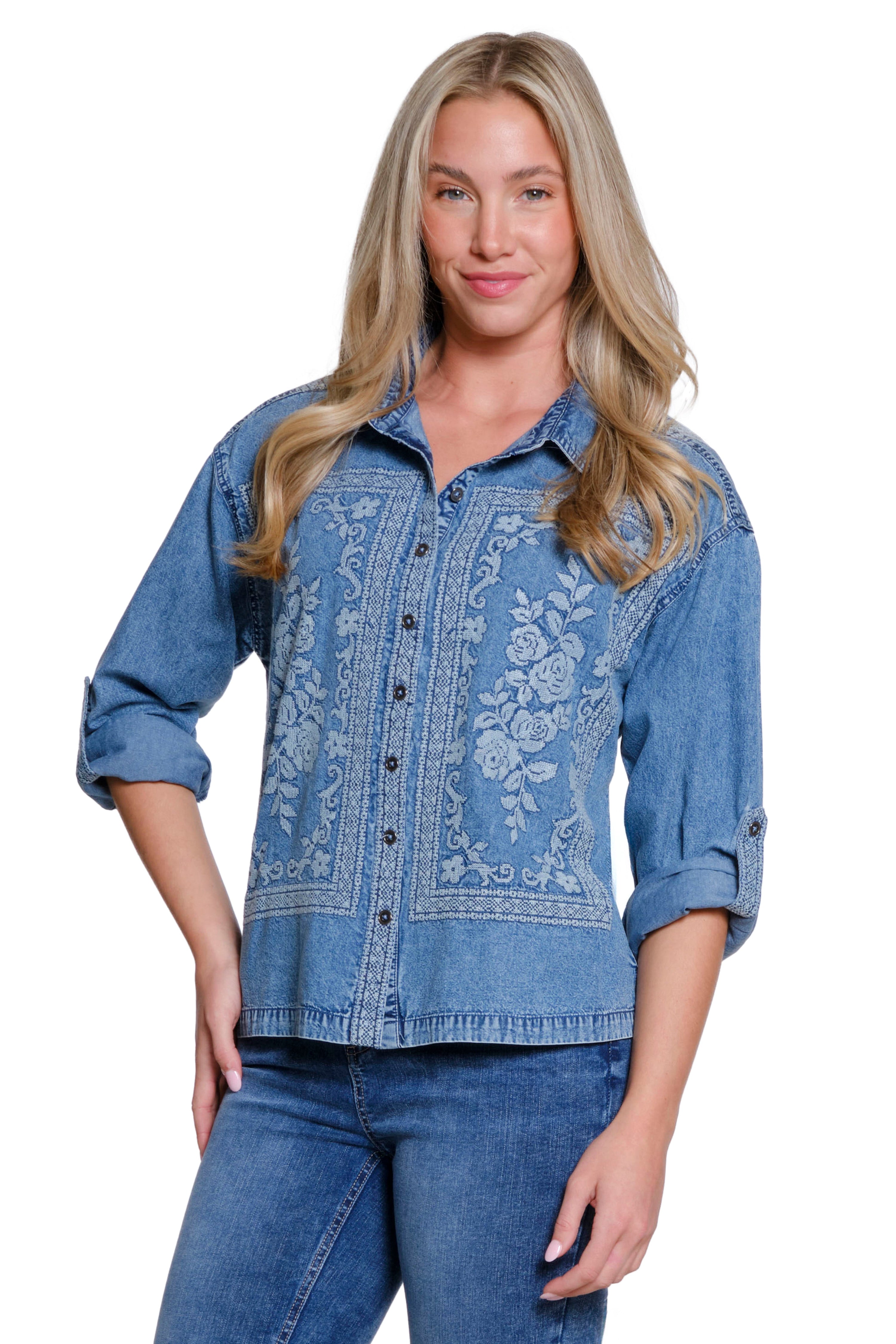 Woman wearing a blue denim shirt with floral embroidery on a white background
