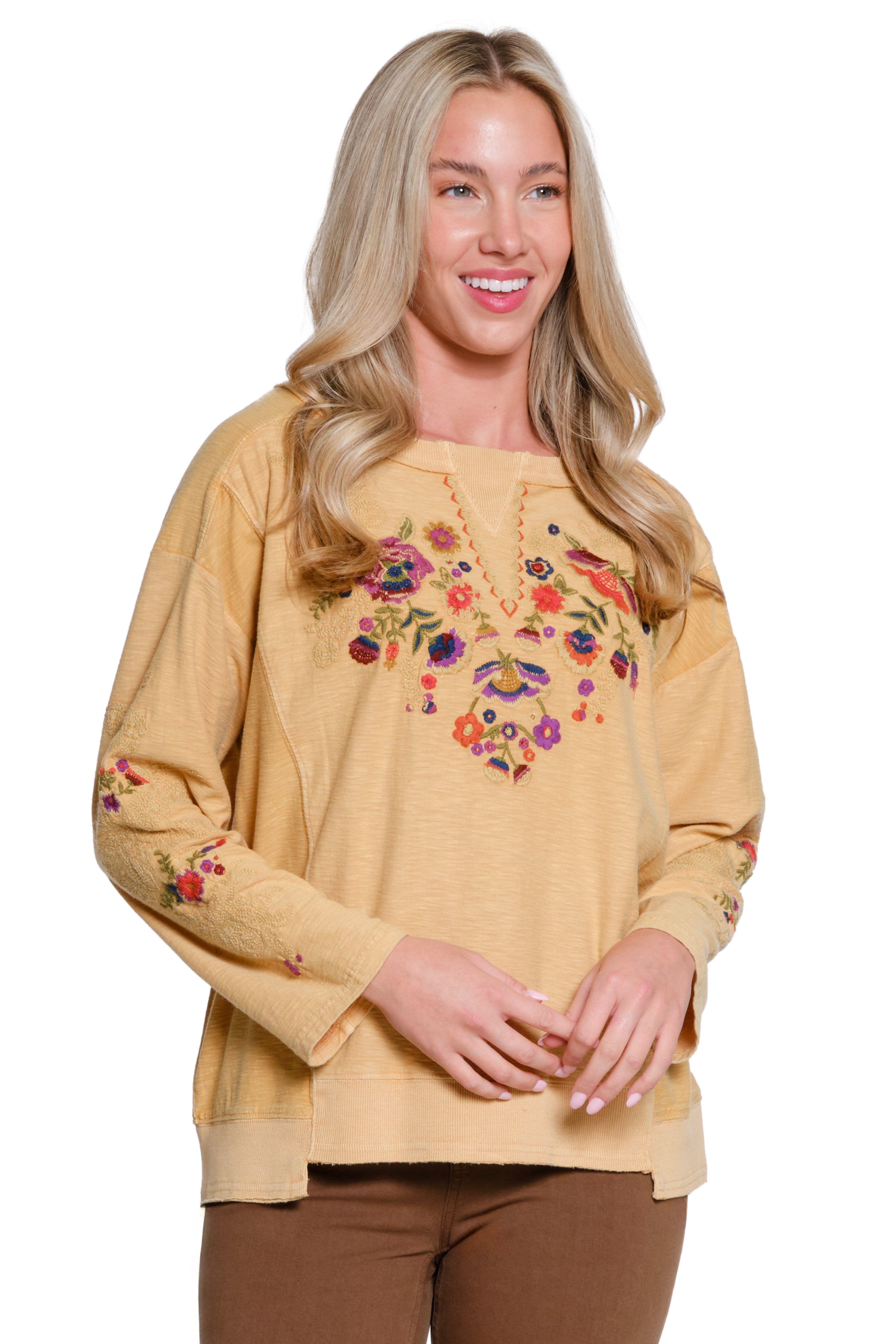 Woman wearing a beige sweater with floral embroidery on a white background